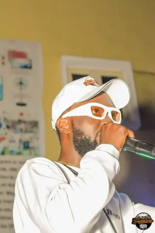 A performer wearing white sunglasses holding a microphone